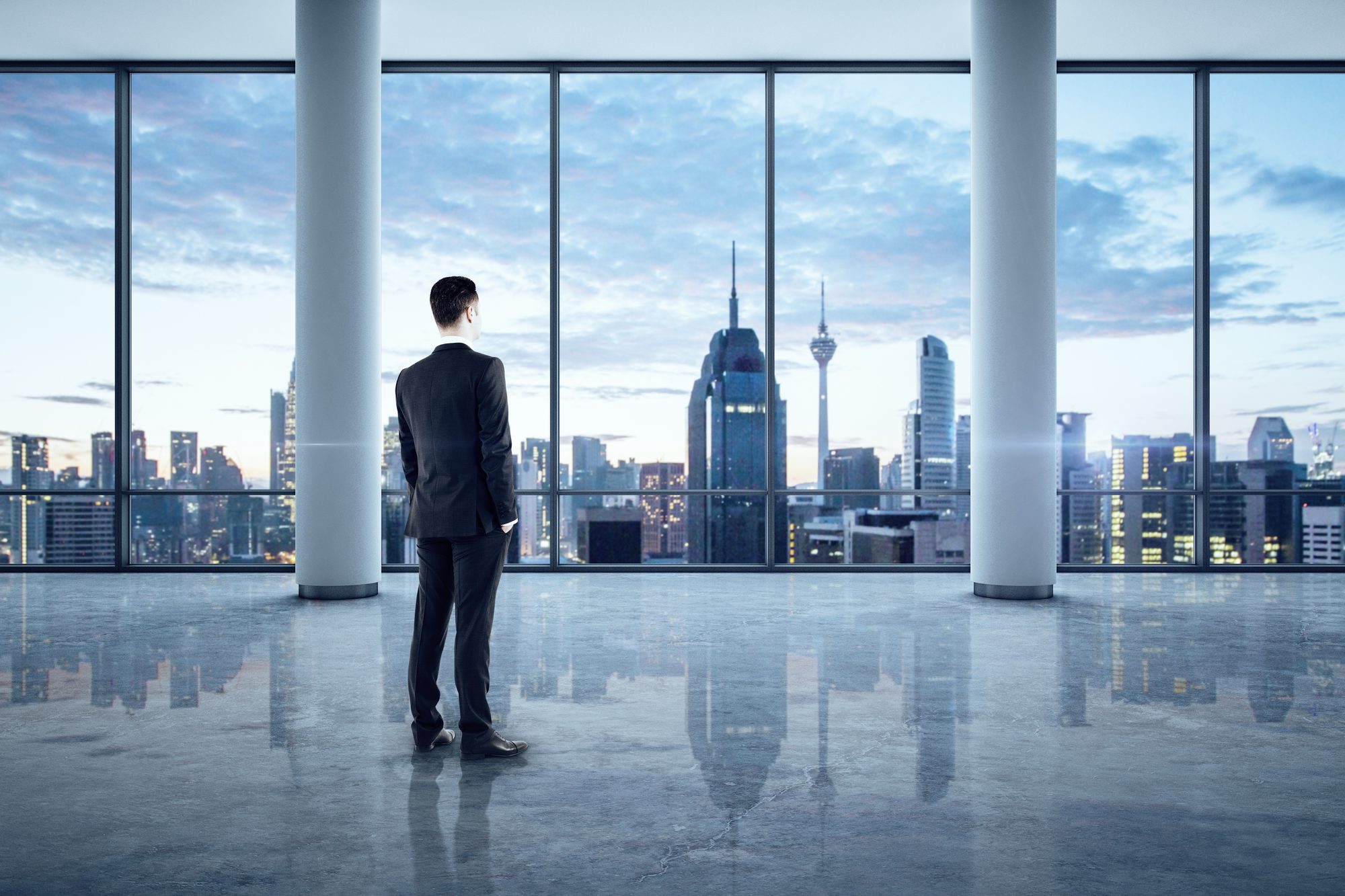 Mann im Anzug blickt aus einem Bürofenster über die Skyline, Sinnbild dafür, wie Macht das Annäherungssystem aktiviert und die Hemmung dämpft