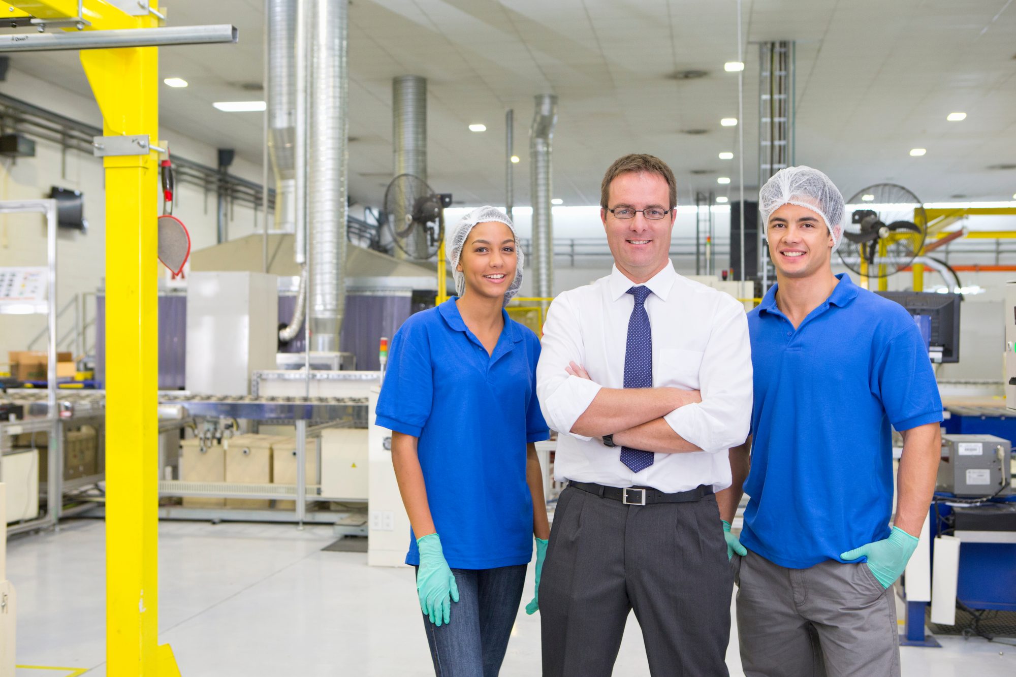 Werkleiter steht mit seinem Team in der Fertigungshalle, Sinnbild für das mittlere Management, das Veränderungen übersetzen und emotional abfedern muss
