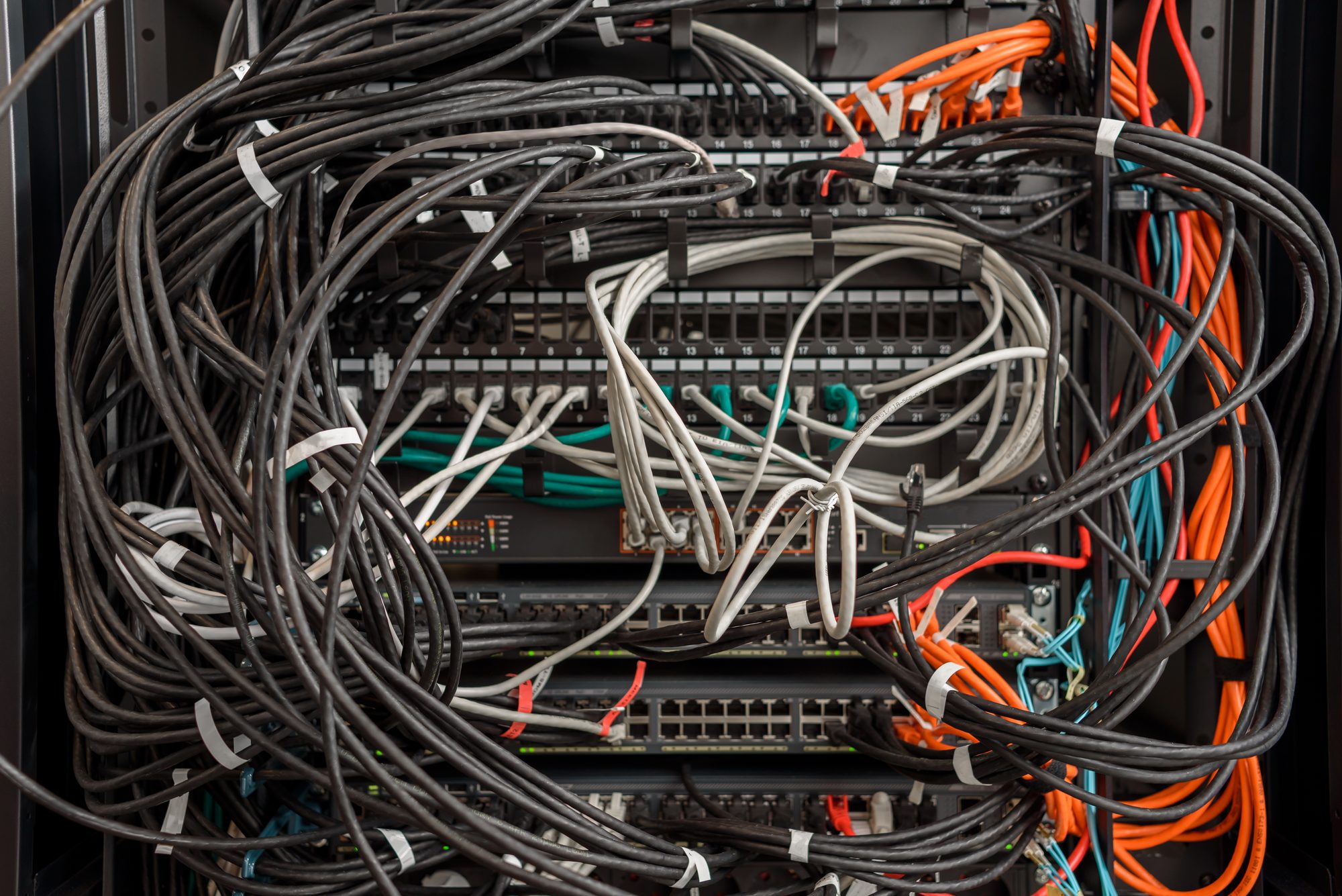Verknotete Netzwerkkabel in einem Serverschrank, Sinnbild für die Kommunikationswege, die nach Brooks' Gesetz mit jedem zusätzlichen Teammitglied explodieren