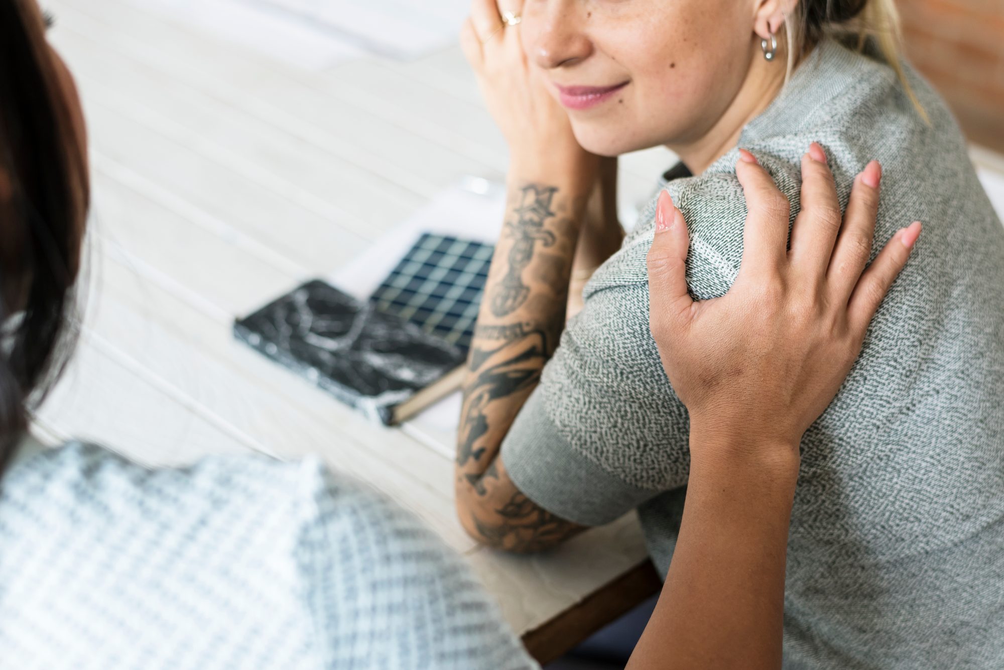 Hand einer Freundin liegt tröstend auf der Schulter einer Frau, Sinnbild für das Annehmen von Trost nach emotionaler Vernachlässigung