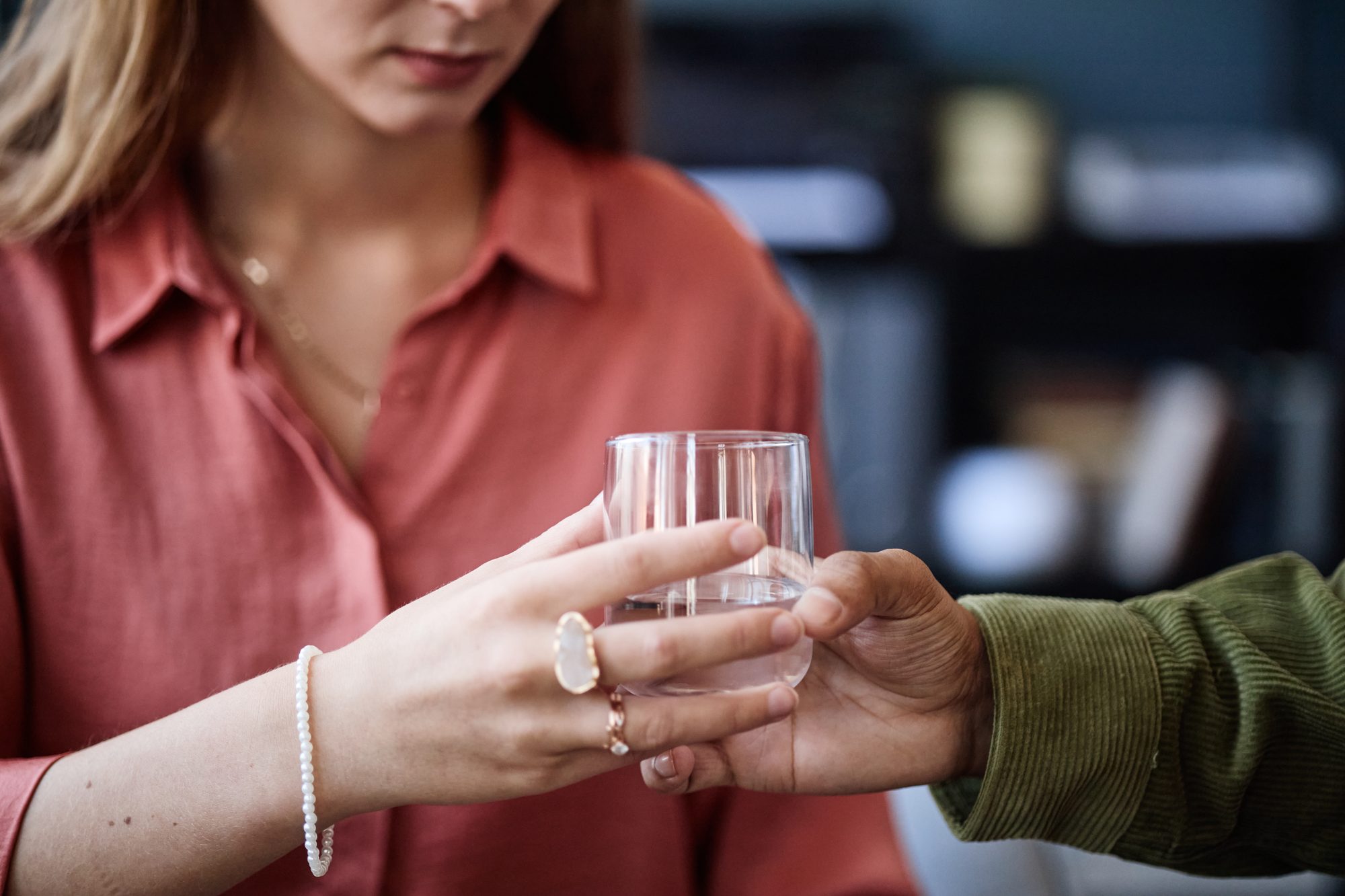 Hand reicht einer Frau ein Glas Wasser über den Tisch, Sinnbild für einen Reparaturversuch nach dem Streit