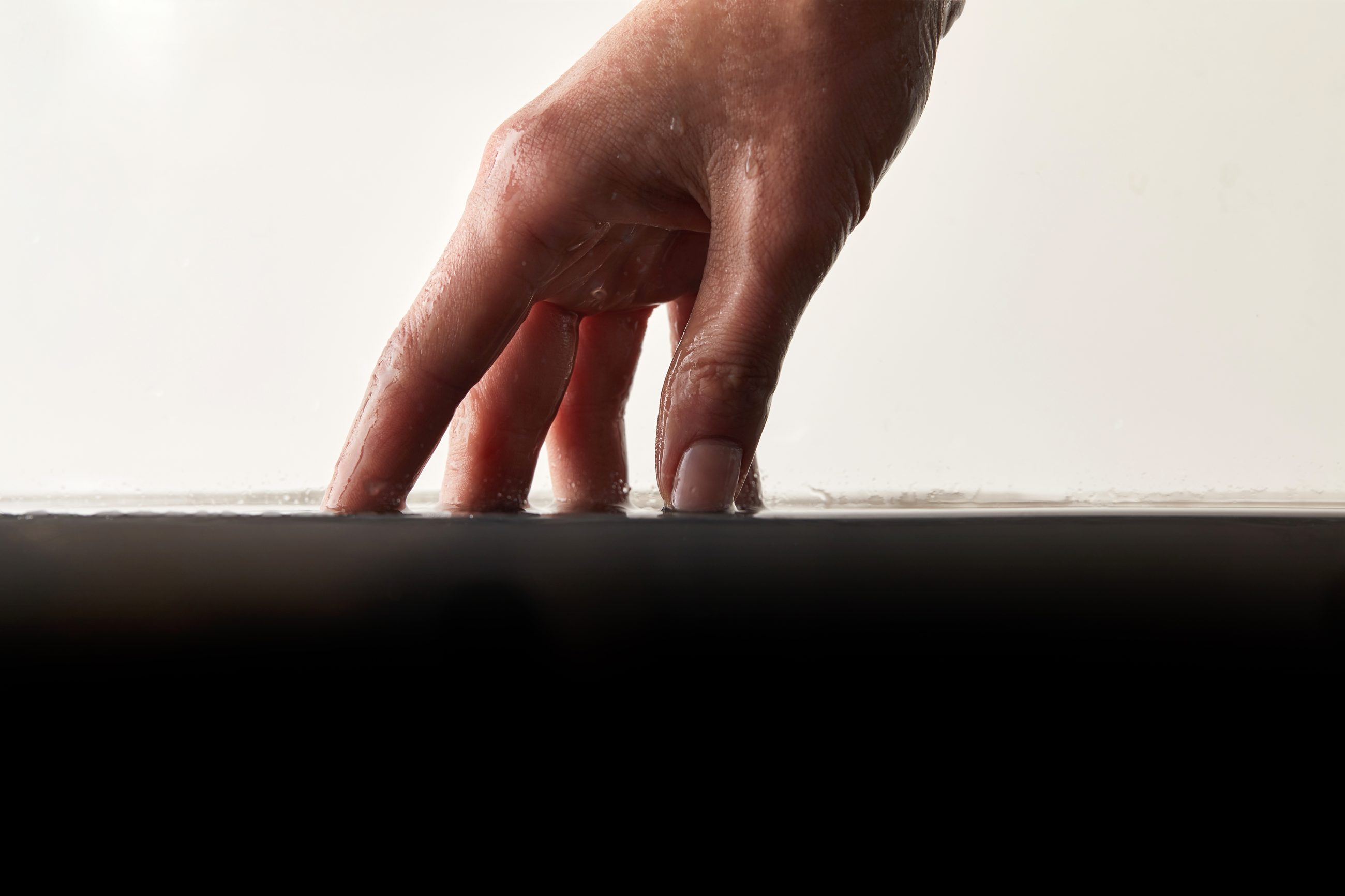 Hand klopft mit den Fingern auf eine dunkle Oberfläche, Sinnbild für das Tapper-Experiment und den Fluch des Wissens in der Kommunikation von Führungskräften
