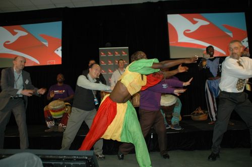 A lively outdoor African cultural festival with dancers and drummers performing under the sun. Spectators surround the performers, clapping and enjoying the vibrant celebration. #AfricanFestival #OutdoorPerformance #CultureInMotion #LiveDrumming #AfricanCelebration