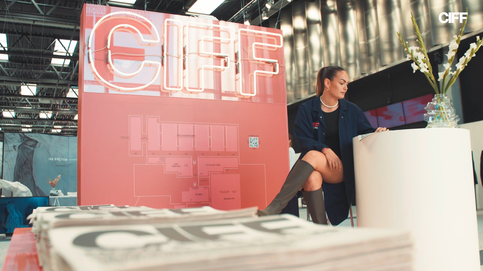 CIFF-neonskilt over messeplanen i Bella Center, med en stak CIFF-aviser i forgrunden