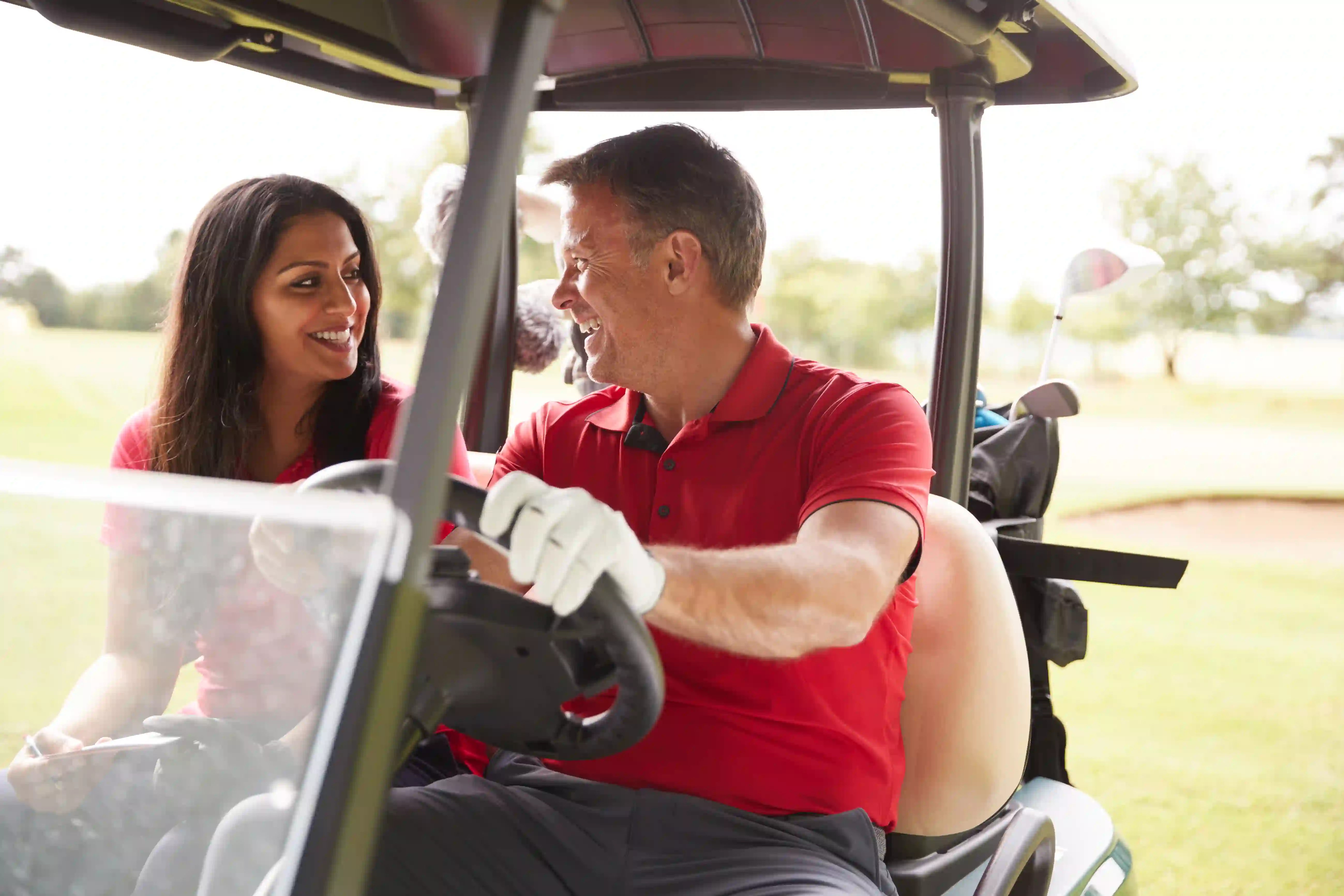mature couple driving golf cart