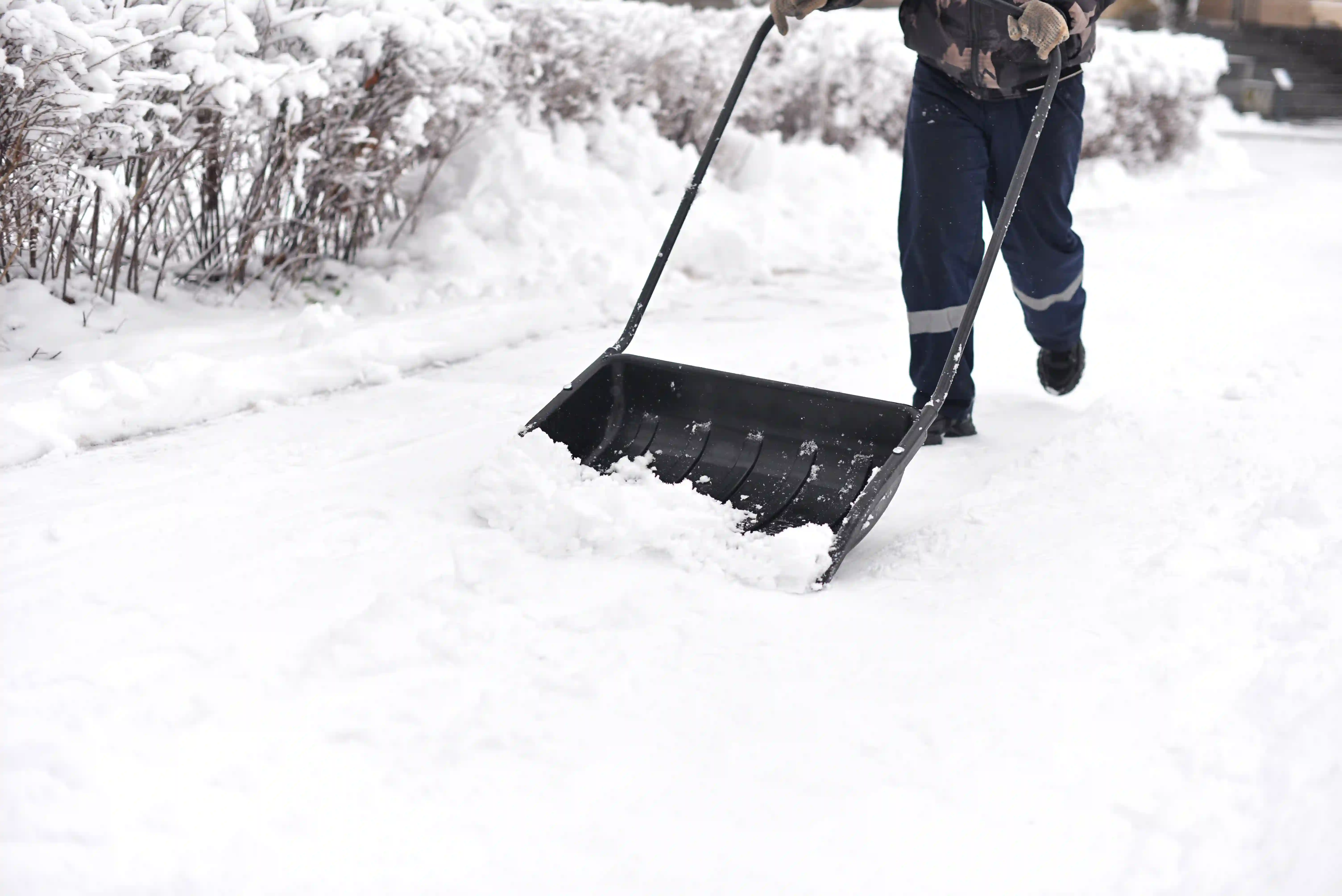 man shovelling deep snow on driveway