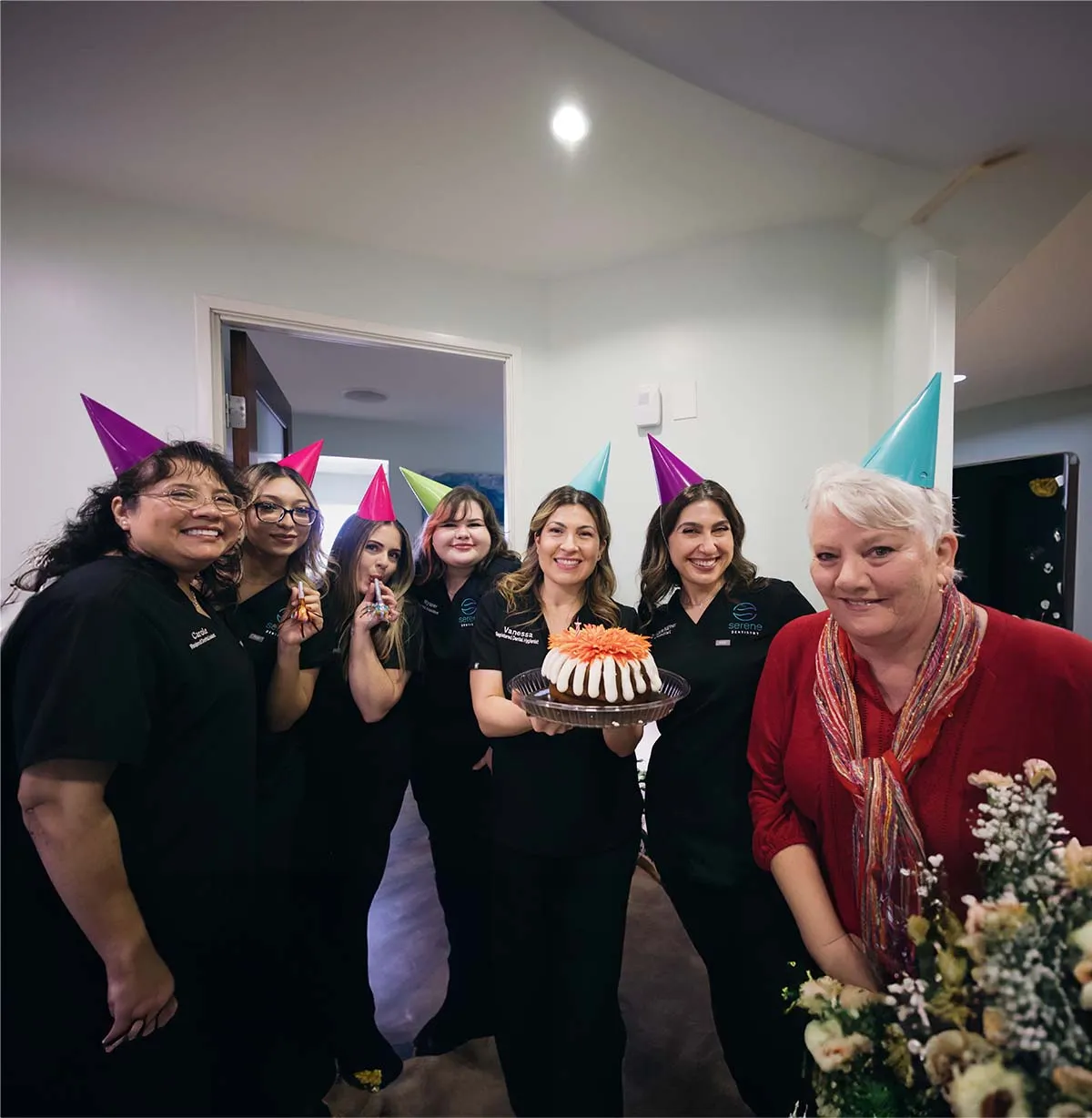 The Serene Dentistry team celebrating together with cake and party hats in Ventura, CA