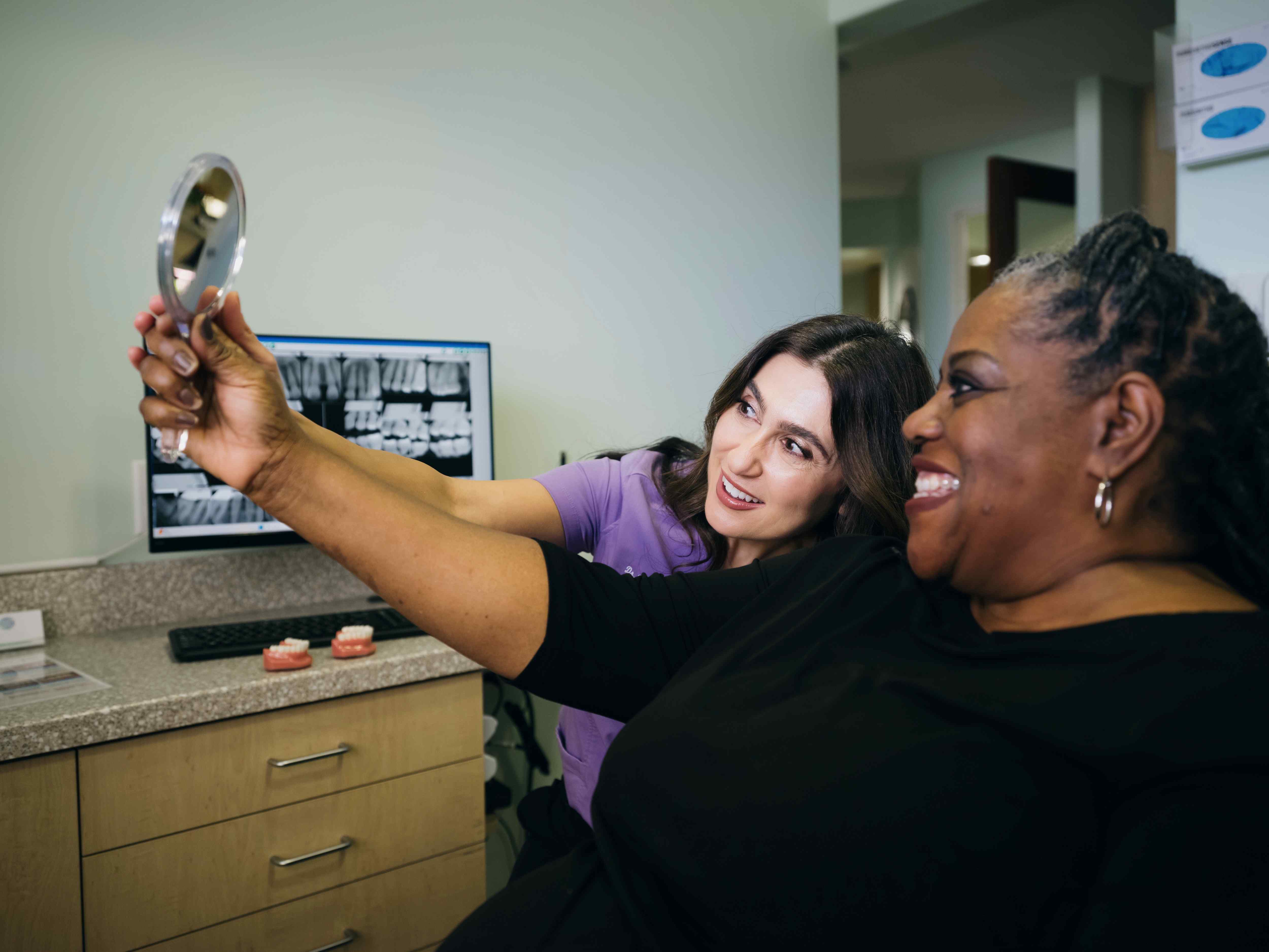 A smiling patient checking out the results of her smile makeover