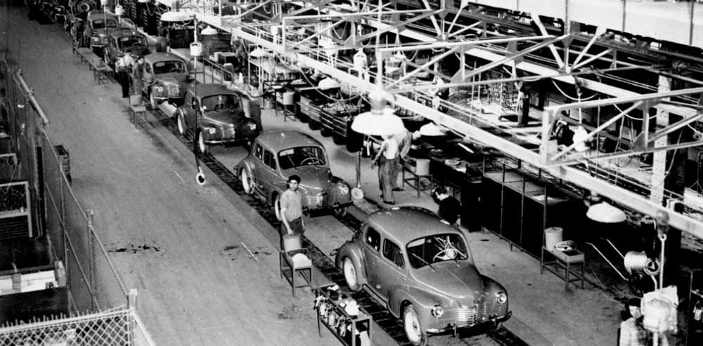 Black and white photo of a car assembly line.