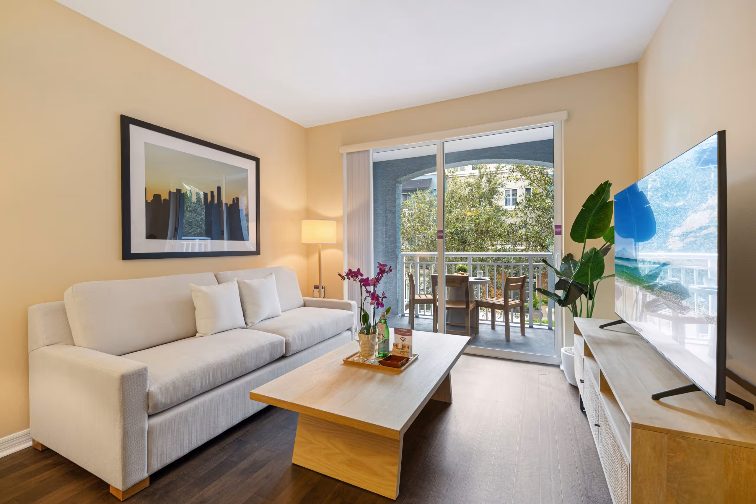 Bright living area at Red Road Commons with a wooden coffee table and private balcony. Starting from $157.