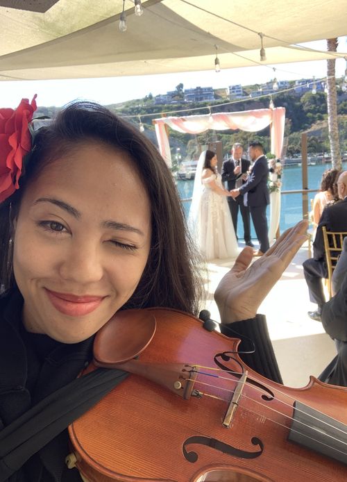 Baethoven smiling and winking while gesturing toward bride and groom holding hands at wedding ceremony