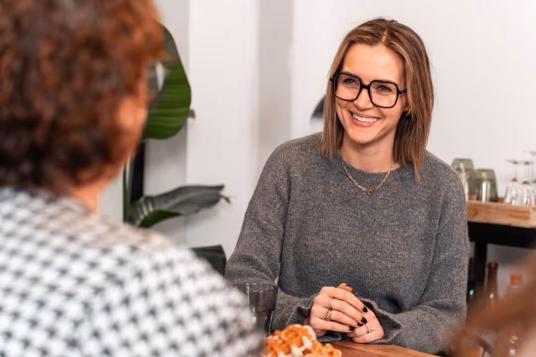 A smiling young woman with large glasses.