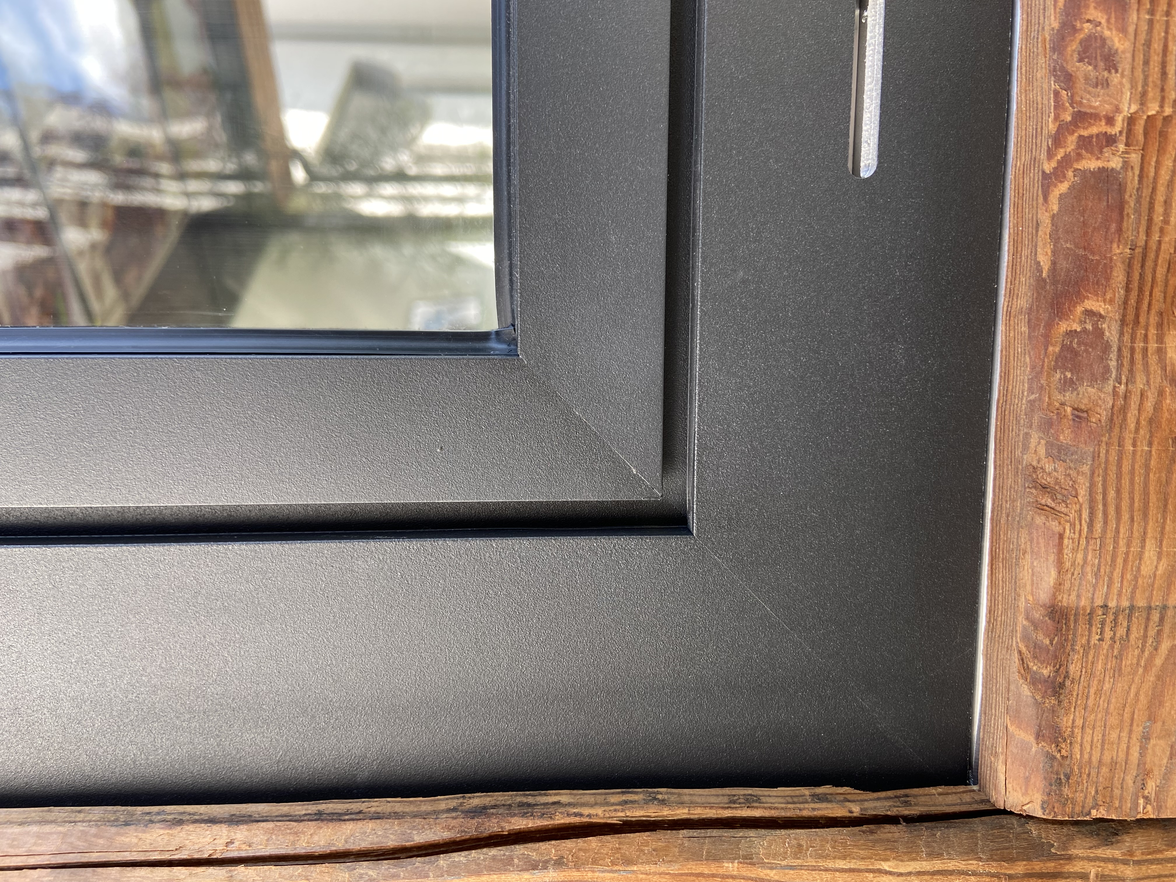 Detailaufnahme eines schwarzen Aluminiumfensterrahmens mit Holzanschluss