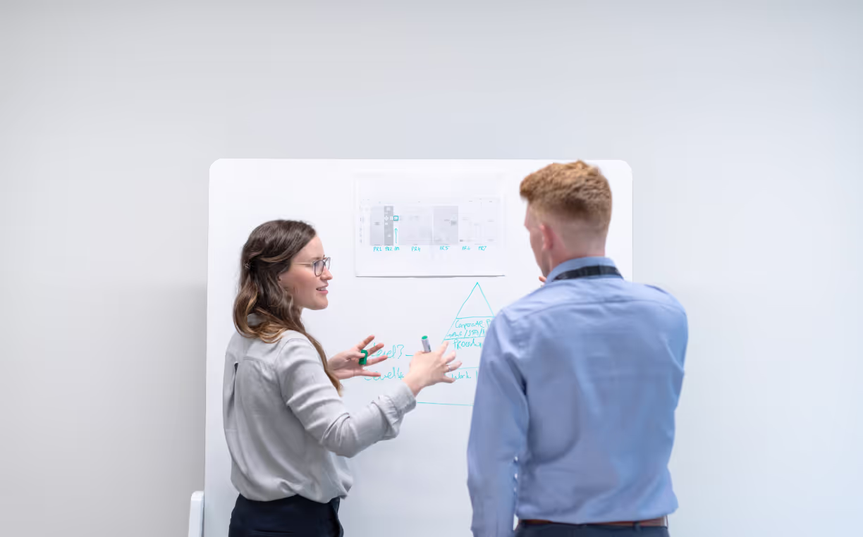 Two people talking over whiteboard with graphs on it