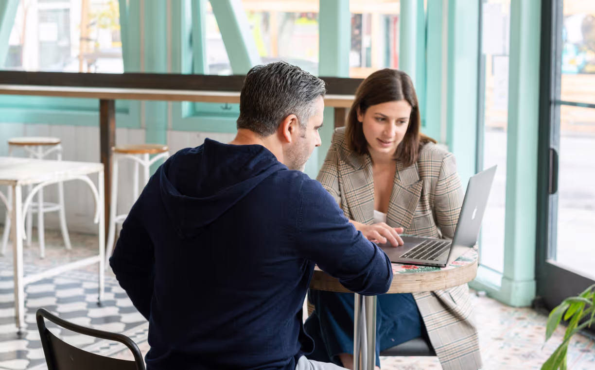 Two people talking over laptop