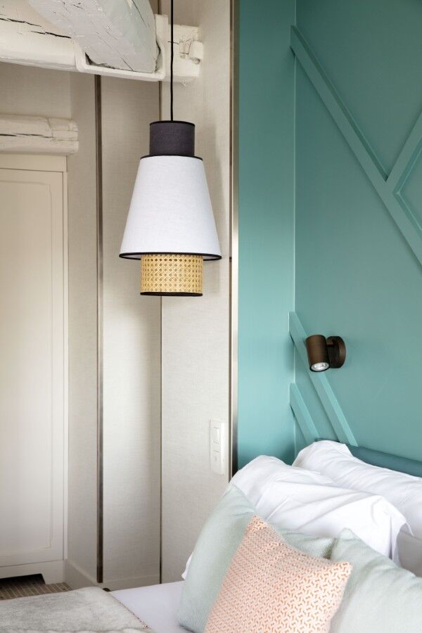 Détail de la chambre Deluxe avec lit, tête de lit turquoise et suspension décorative