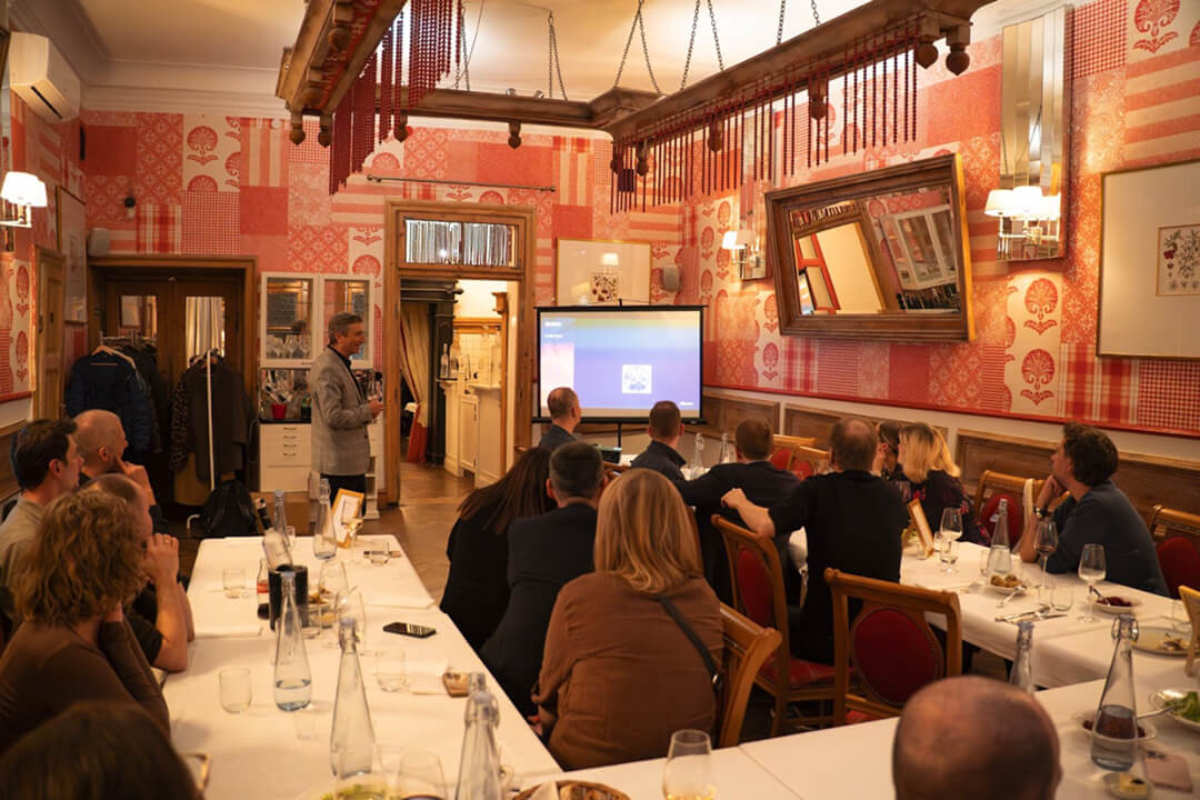 An image of company dinner showing people sitting behind the table watching a presentation