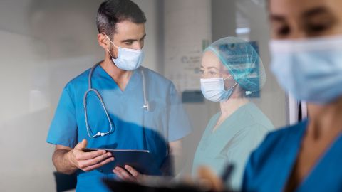 Deux professionnels de santé masqués échangent des informations à l’aide d’une tablette.