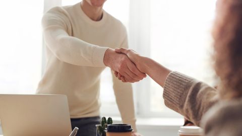 Deux personnes se serrent la main dans un cadre professionnel lumineux.