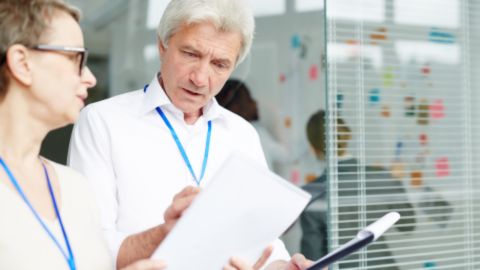 Deux professionnels échangent autour de documents lors d’une discussion de travail.