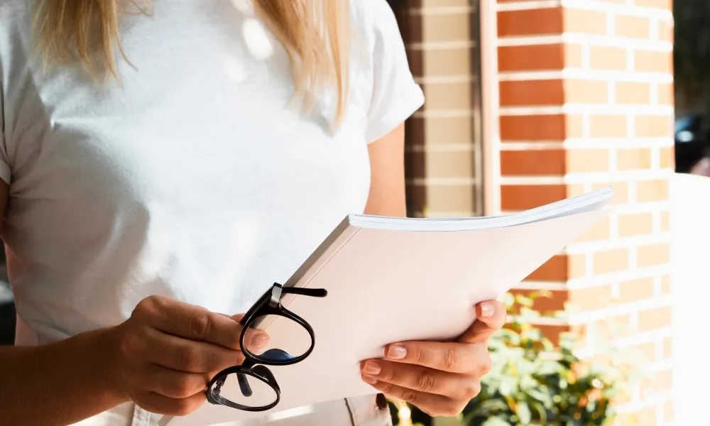 femme tenant des lunettes et un dossier