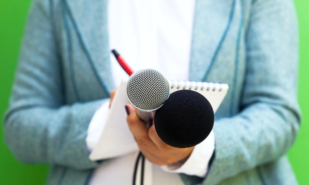 personne qui prend des notes qui tend un microphone