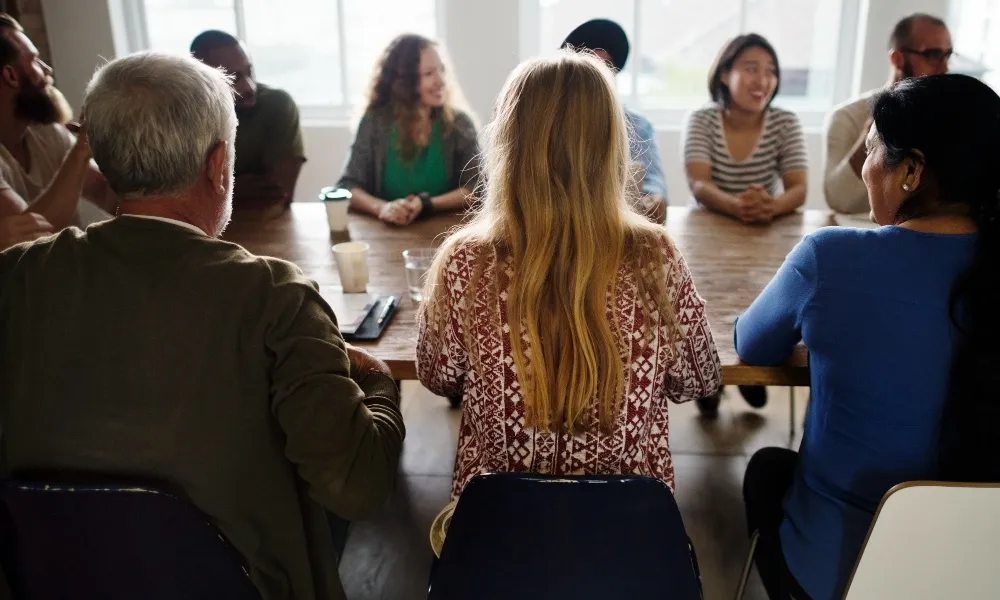 Une dizaine de personnes sont réunis autour d'une table en bois