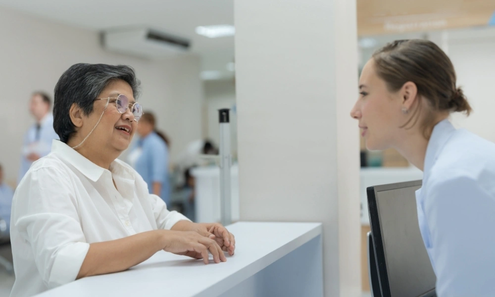 Une dame âgée est au présentoir et discute avec un professionnel de santé