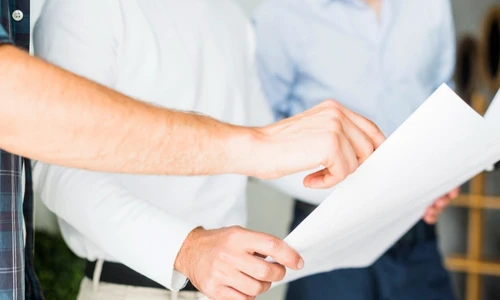 Une personne tient un papier et la seconde pointe du doigt ce papier