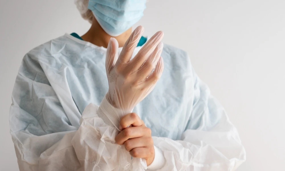 Personne en tenue de bloc opératoire qui met ses gants