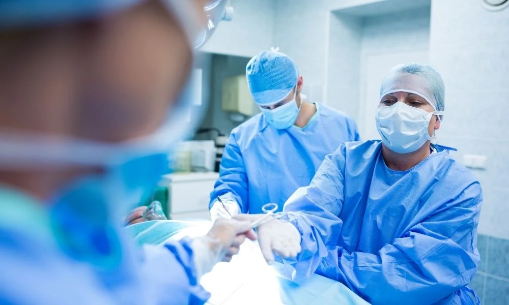 Une équipe médicale en salle d’opération s’échange un instrument pendant une intervention chirurgicale.