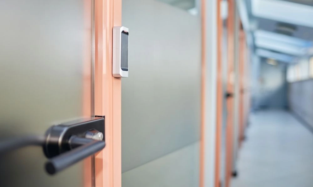 Vue en gros plan de la poignée et du système de verrouillage électronique d'une porte située dans un couloir d'établissement.