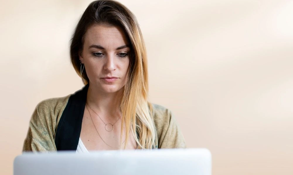 Femme au regard concentré sur son ordinateur portable.