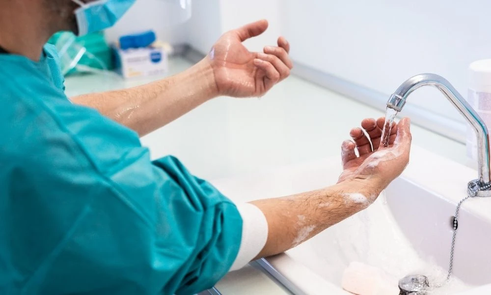 Un professionnel de santé se lave soigneusement les mains au lavabo pour prévenir les infections.