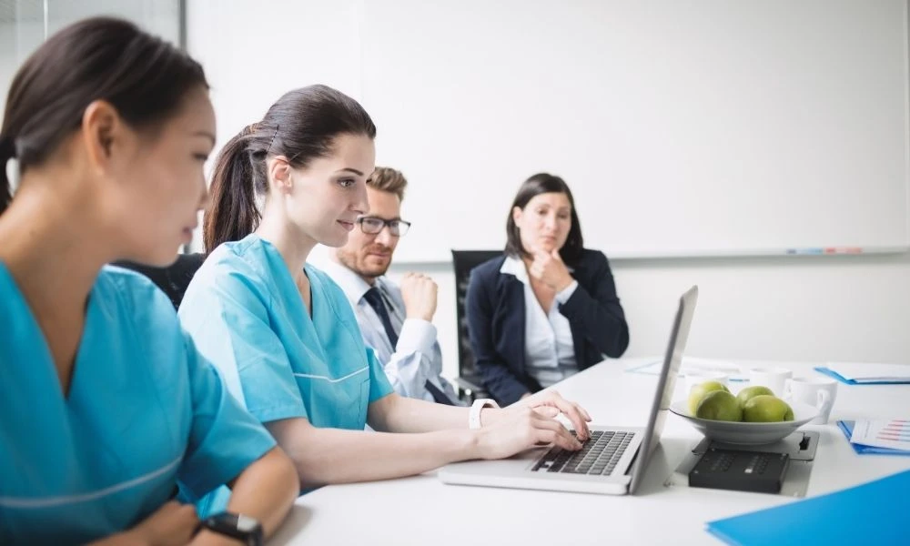 Des professionnels de santé et des cadres échangent autour d’un ordinateur lors d’une réunion de travail.
