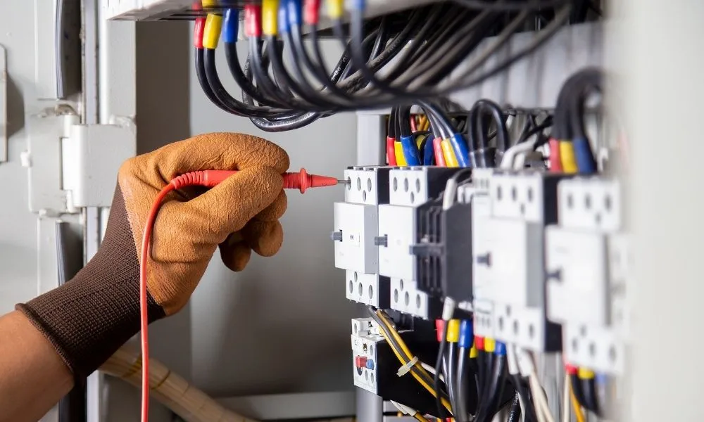 Technicien effectuant un contrôle électrique sur un tableau de disjoncteurs