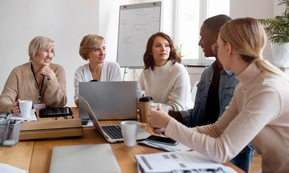 Équipe de professionnels réunis autour d'une table de réunion, échangeant lors d'une séance de travail collaboratif.