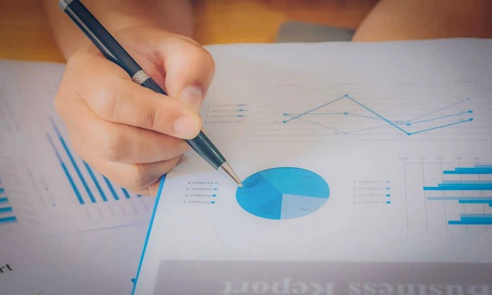 Une personne pointe un stylo vers un graphique circulaire sur un rapport d’indicateurs.