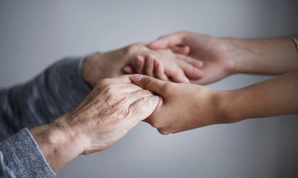 Deux personnes se tiennent les mains avec bienveillance, illustrant le soutien et la confiance.