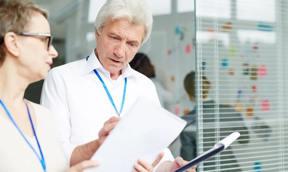 Deux professionnels échangent autour de documents lors d’une discussion de travail.