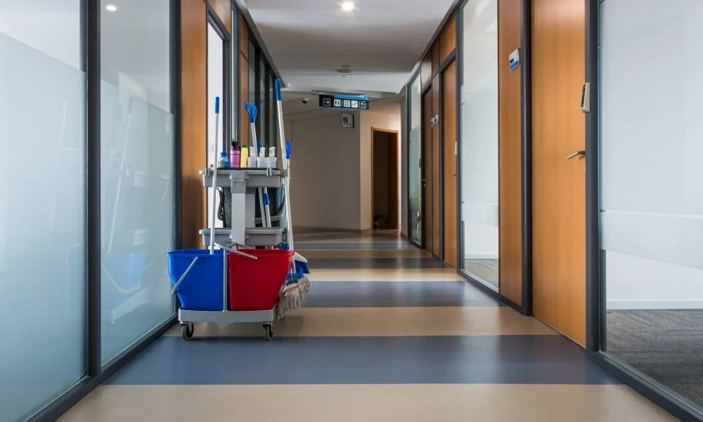 Un chariot de nettoyage est stationné dans le couloir propre et lumineux d’un établissement.