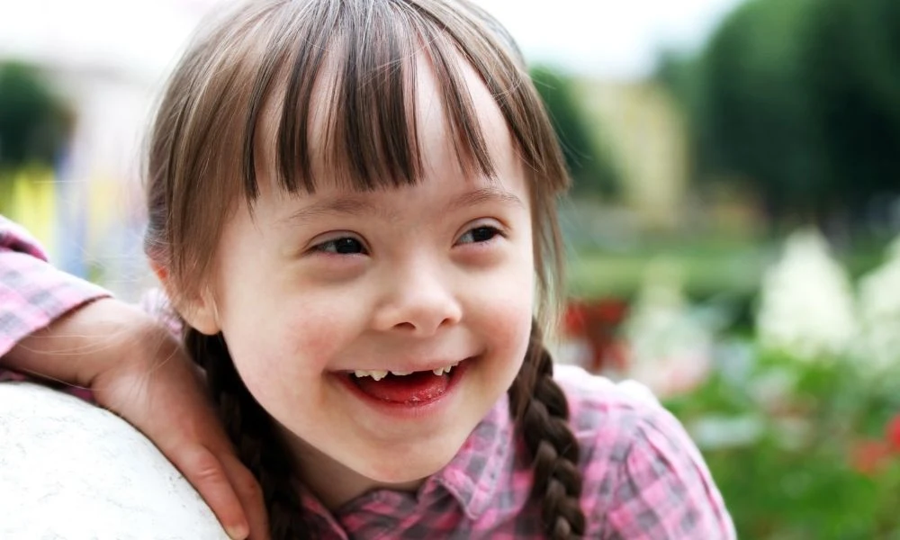 Une fillette souriante aux tresses brunes profite d’un moment en extérieur.