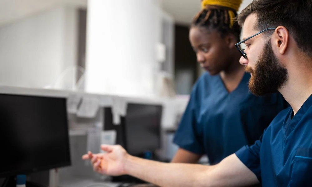 Deux professionnels de santé collaborent devant un écran d’ordinateur.