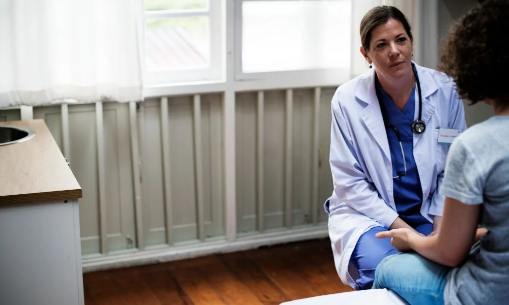 Une médecin écoute attentivement une patiente dans un cadre calme et professionnel.