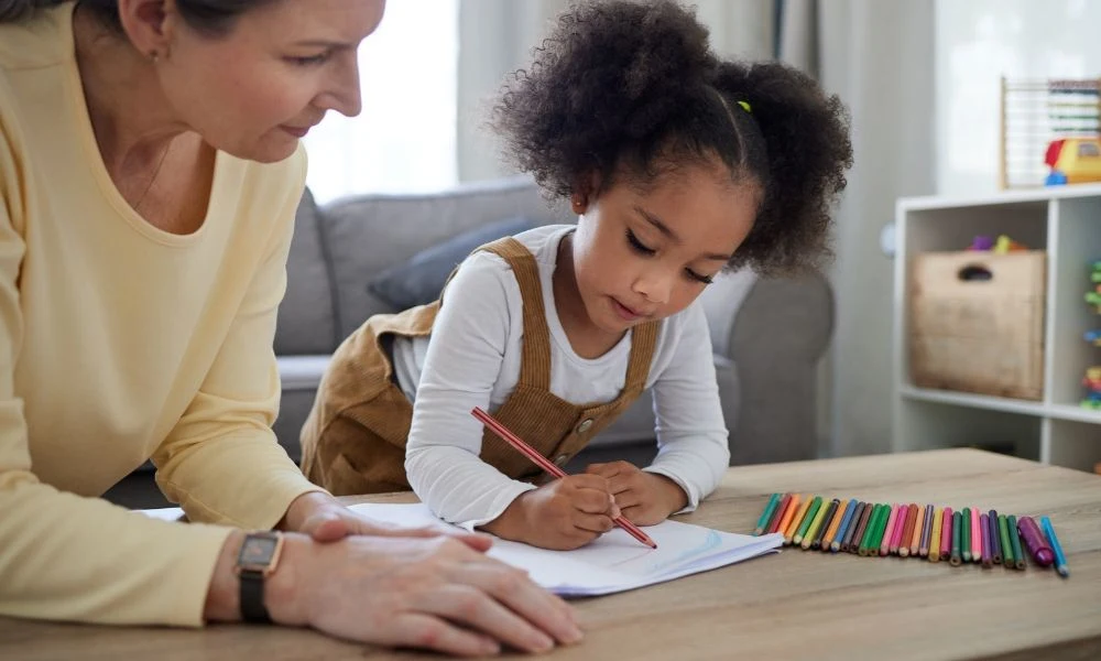 Une adulte aide une petite fille à faire ses devoirs