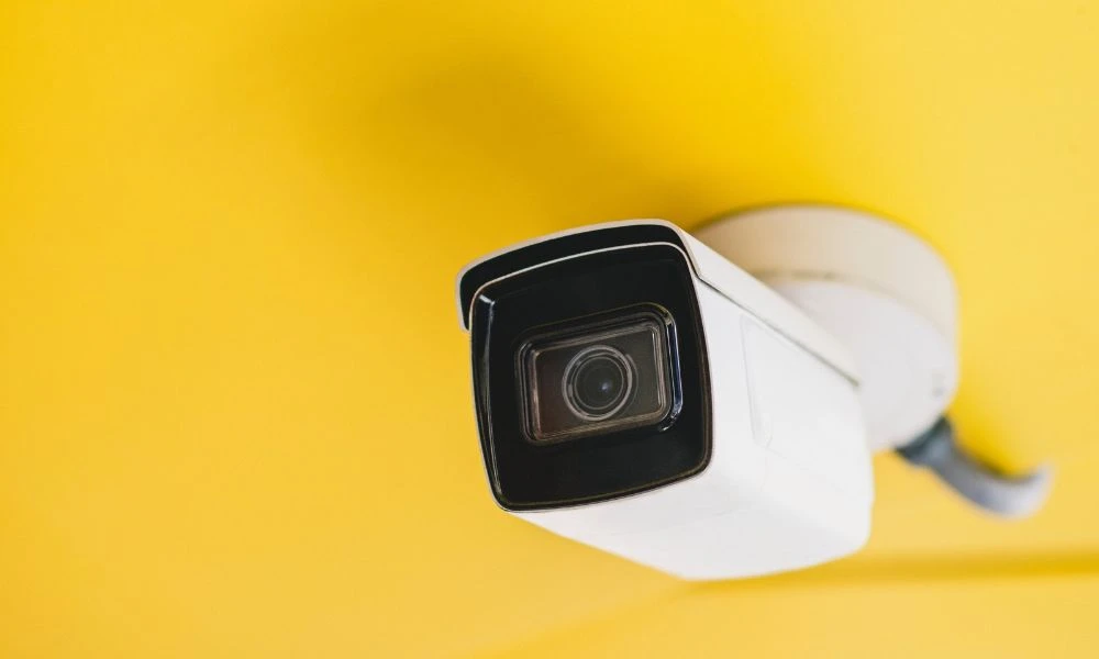 Caméra de surveillance fixée sur un plafond de couleur jaune.