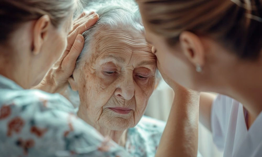 Portrait dame âgée entourée par deux autres femmes qui lui offrent du soutien.