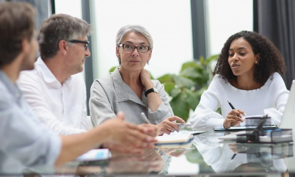 Des collègues échangent autour d’une table de réunion lors d’une discussion professionnelle.