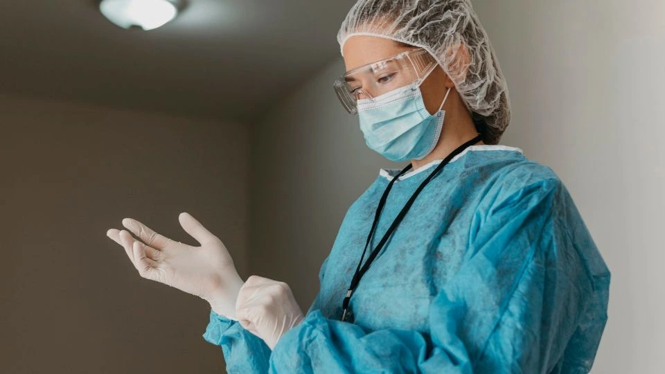 Une infirmière met ses gants de protection avant d’intervenir auprès d’un patient.
