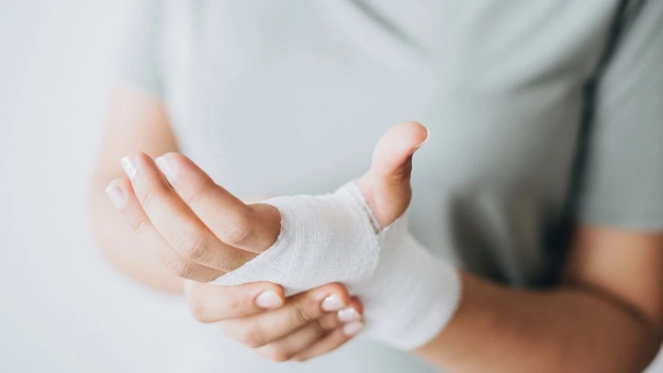 Une personne tient sa main bandée, illustrant une blessure ou un accident de travail.